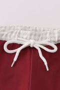 Maroon swim trunks with playful elephant embroidery, perfect for beach fun.