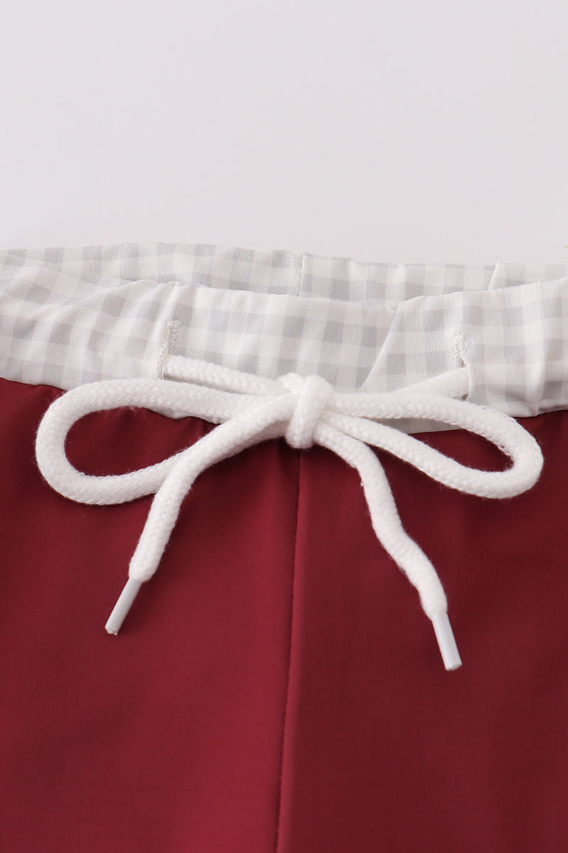 Maroon swim trunks with playful elephant embroidery, perfect for beach fun.
