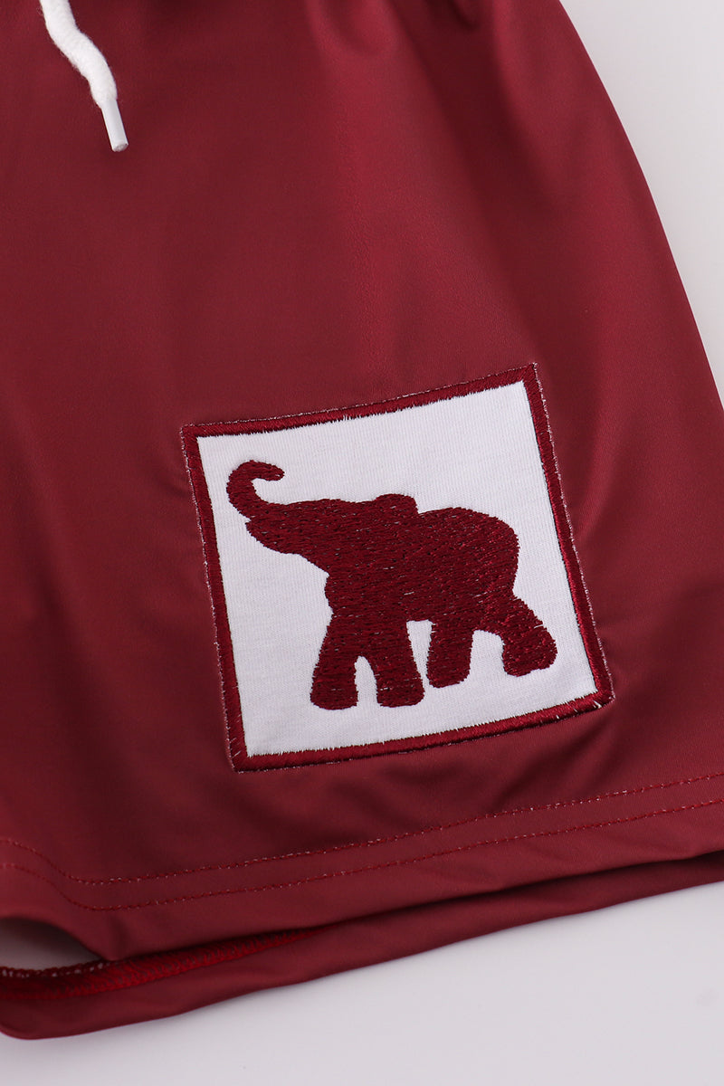 Maroon swim trunks with playful elephant embroidery, perfect for beach fun.