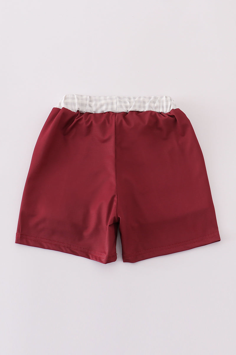 Maroon swim trunks with playful elephant embroidery, perfect for beach fun.