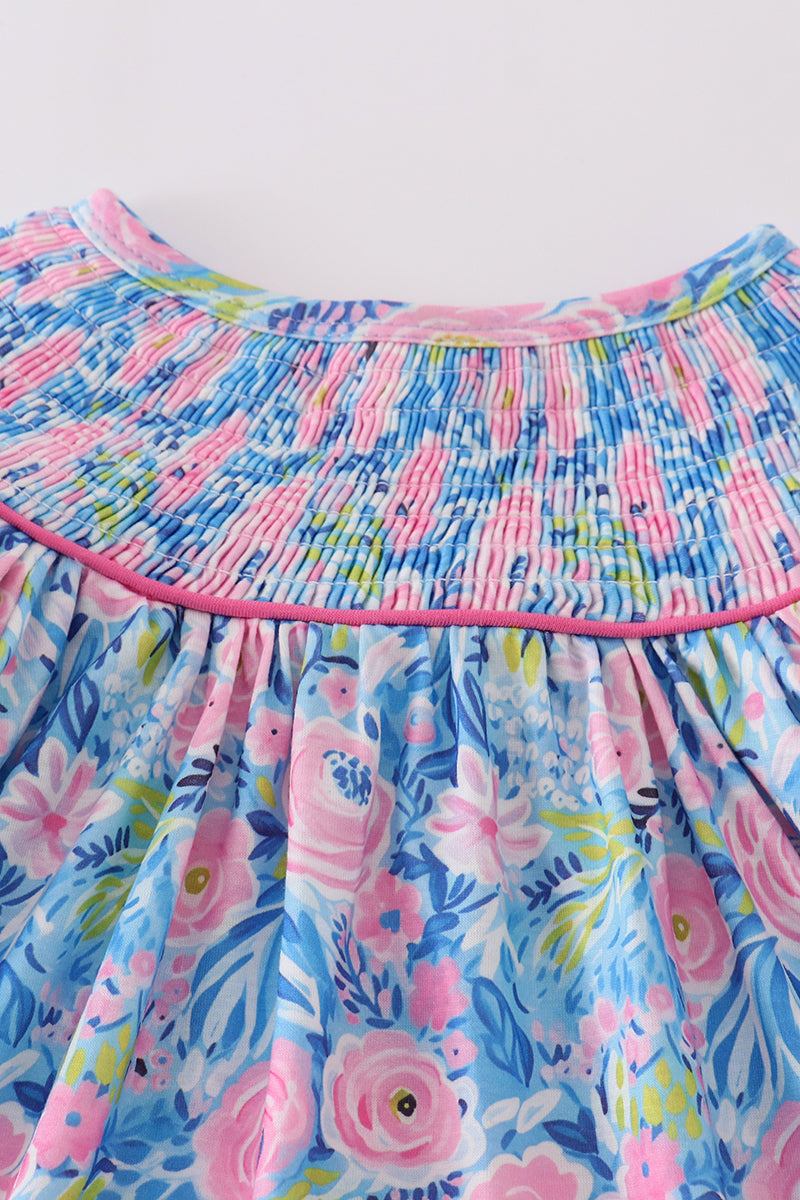 A charming blue dress with floral patterns and delicate smocking, perfect for spring.