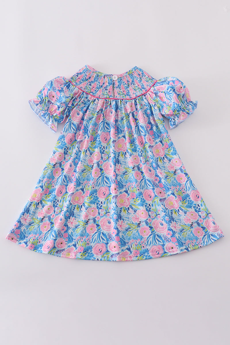 A charming blue dress with floral patterns and delicate smocking, perfect for spring.