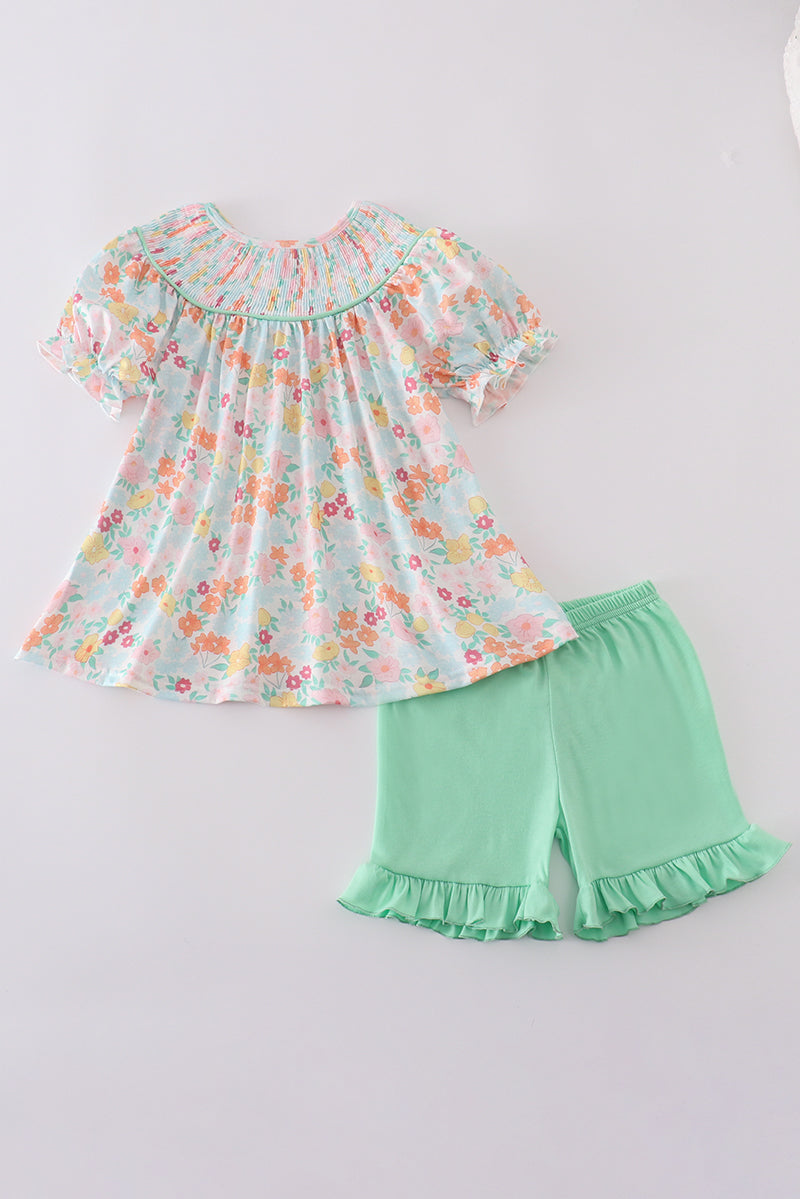 A charming green smocked dress with floral patterns, perfect for springtime adventures.