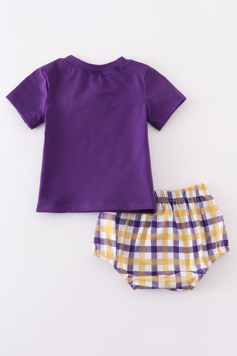 Toddler in a purple and gold LSU bloomer set with ruffled sleeves.