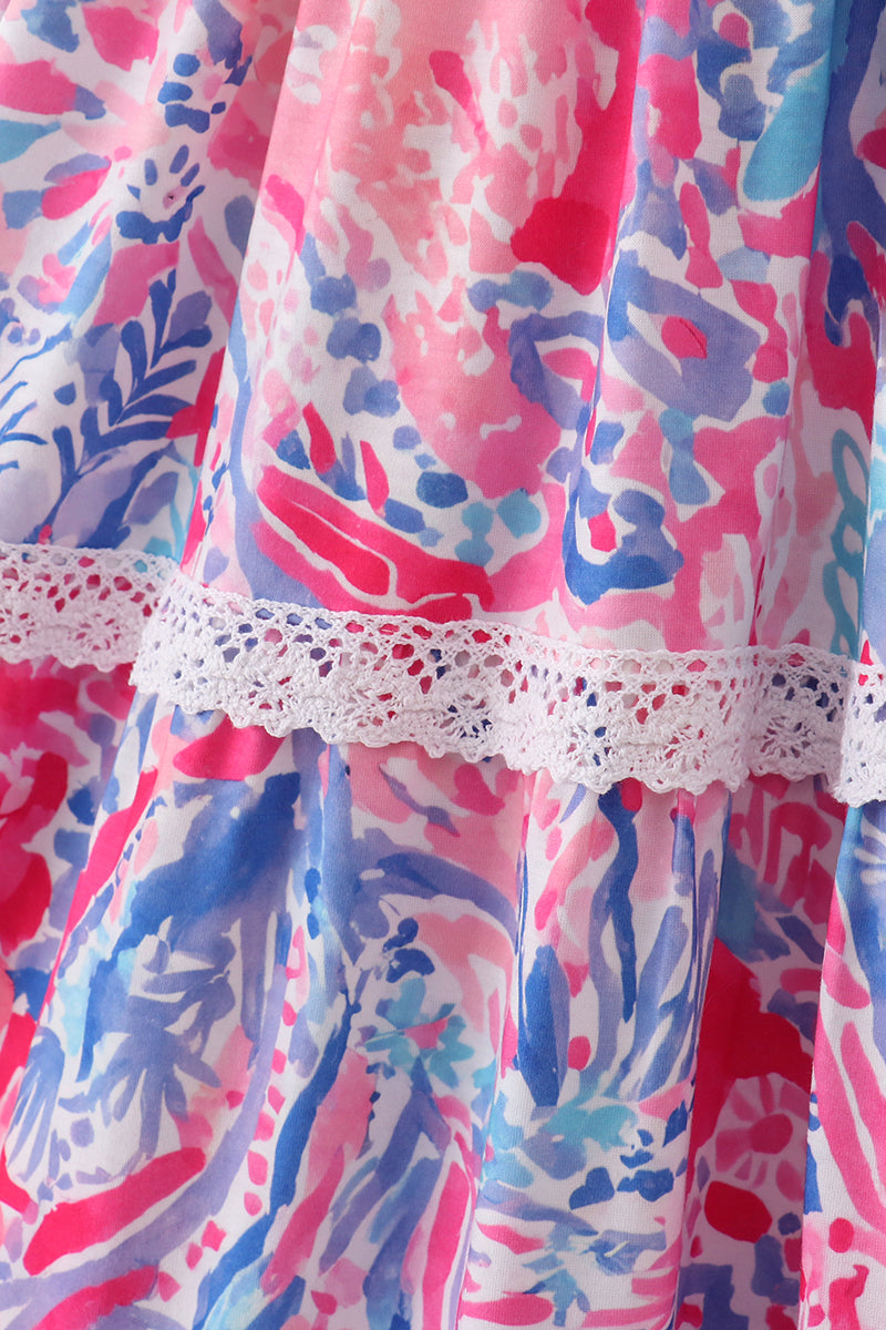 Mom wearing a vibrant tiered dress with tropical sunset wave patterns, perfect for summer.