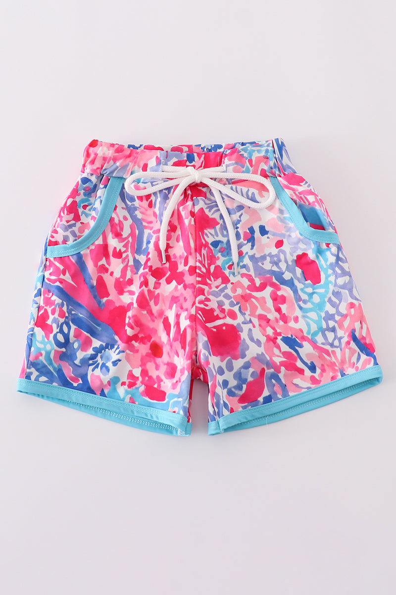 Bright swim trunks with vibrant tropical sunset and ocean wave patterns for kids.