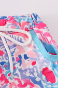 Bright swim trunks with vibrant tropical sunset and ocean wave patterns for kids.
