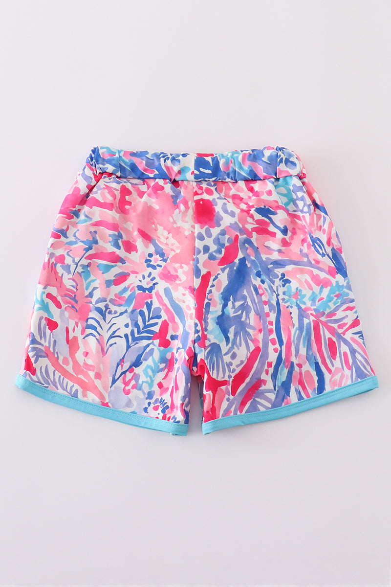 Bright swim trunks with vibrant tropical sunset and ocean wave patterns for kids.