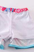 Bright swim trunks with vibrant tropical sunset and ocean wave patterns for kids.
