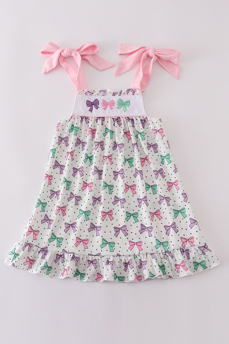 A charming pink dress with bow embroidery and playful ruffle details.