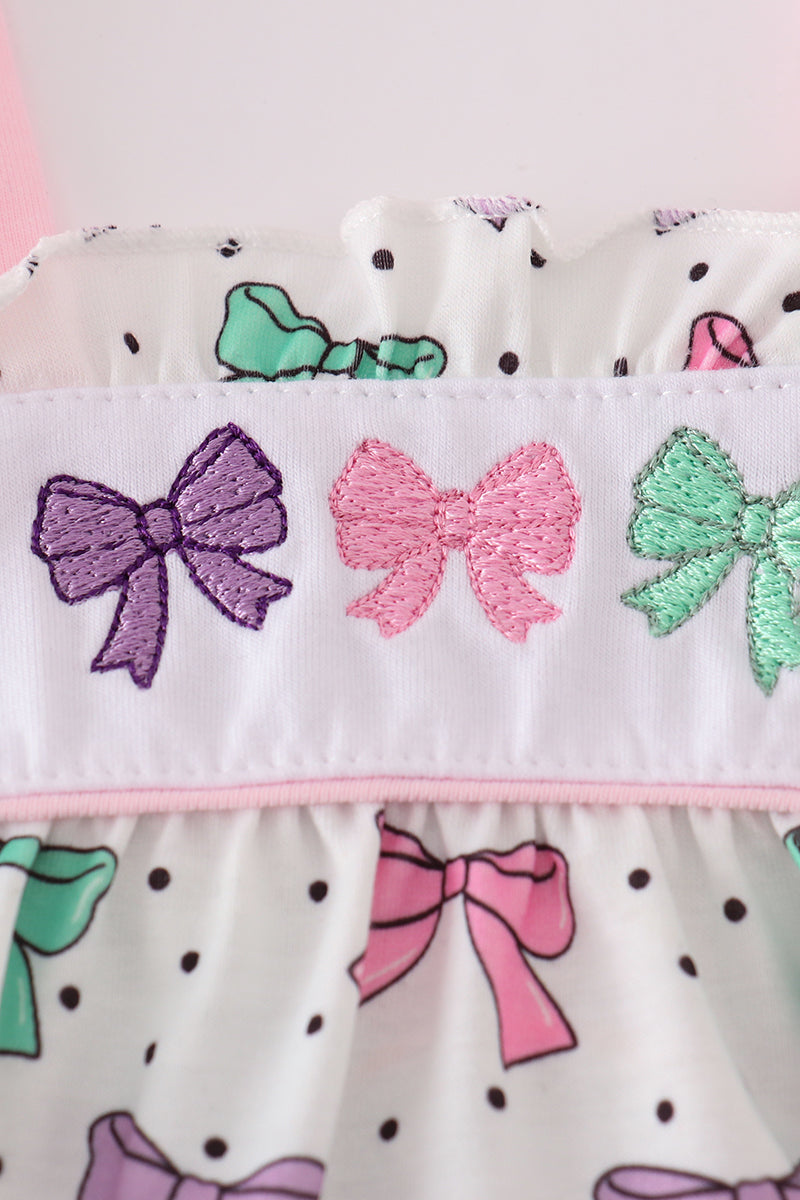 A charming pink dress with bow embroidery and playful ruffle details.