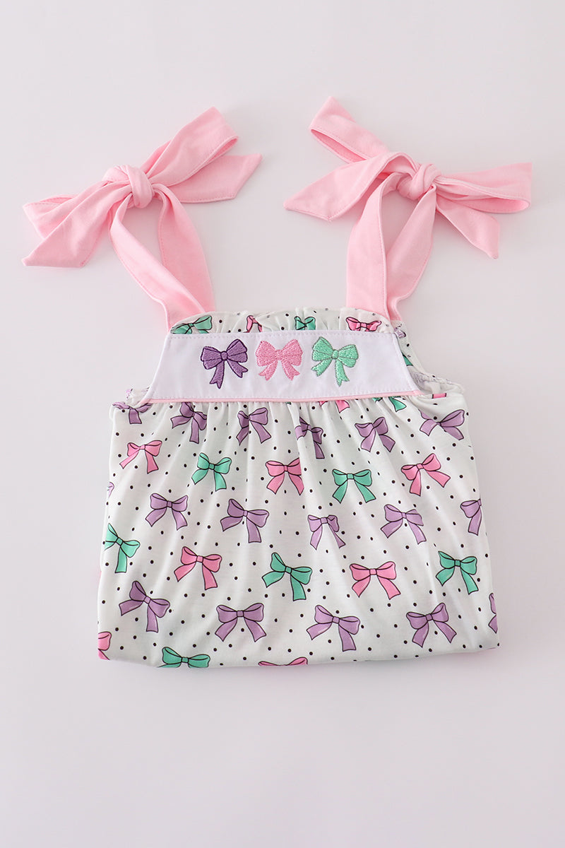 A charming pink dress with bow embroidery and playful ruffle details.