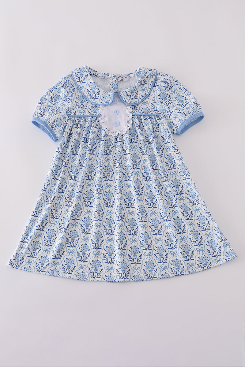 A charming blue toile garden bow dress with a playful floral pattern.
