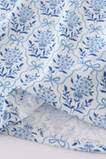 A charming blue toile garden bow dress with a playful floral pattern.