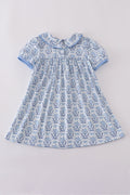 A charming blue toile garden bow dress with a playful floral pattern.