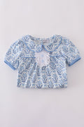 A charming blue toile garden bow dress with a playful floral pattern.